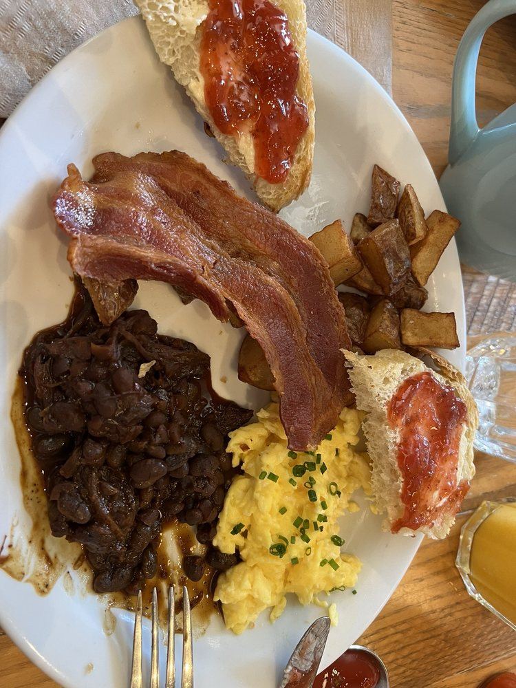 Classic breakfast with scrambled eggs, crispy bacon, sourdough and pork and beans